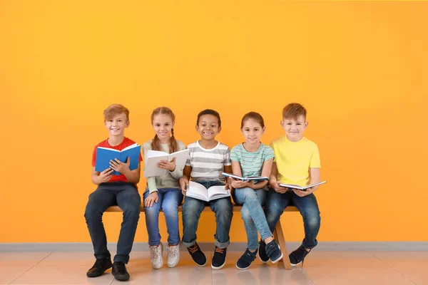 Niedliche kleine Kinder lesen Bücher auf farbigem Hintergrund — Stockfoto