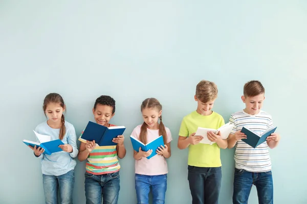 Niedliche kleine Kinder mit Büchern auf farbigem Hintergrund — Stockfoto