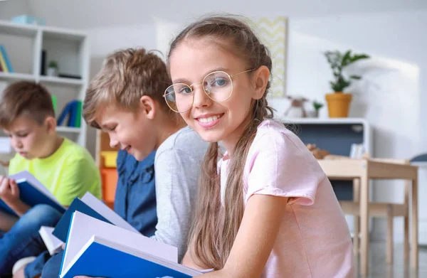 Carino bambina con gli amici a leggere libri al chiuso — Foto Stock