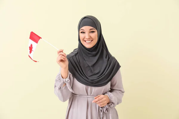 Beautiful Muslim woman with Canadian flag on color background — ストック写真