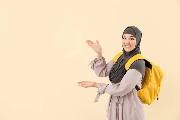 Muslimische Studentin zeigt etwas auf farbigem Hintergrund — Stockfoto