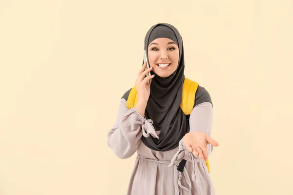 Female Muslim student talking by phone on color background — ストック写真