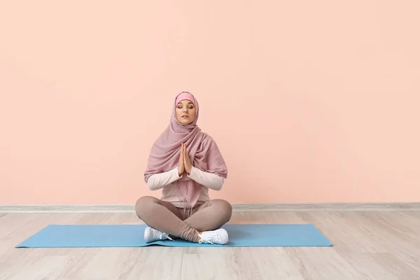 Sportliche muslimische Frau praktiziert Yoga in der Nähe der Farbwand — Stockfoto