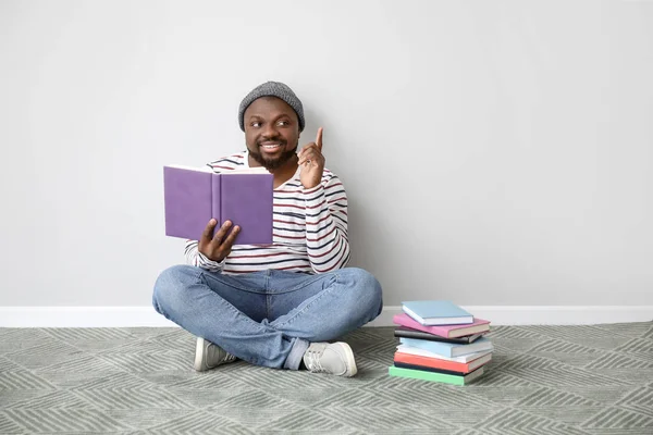 Hombre afroamericano leyendo libro cerca de la pared de luz — Foto de Stock