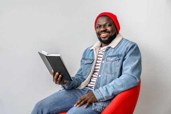 Hombre afroamericano leyendo libro sobre fondo claro — Foto de Stock