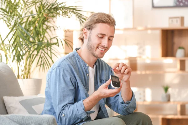 Diabetic man checking blood sugar level at home — Stock Photo, Image