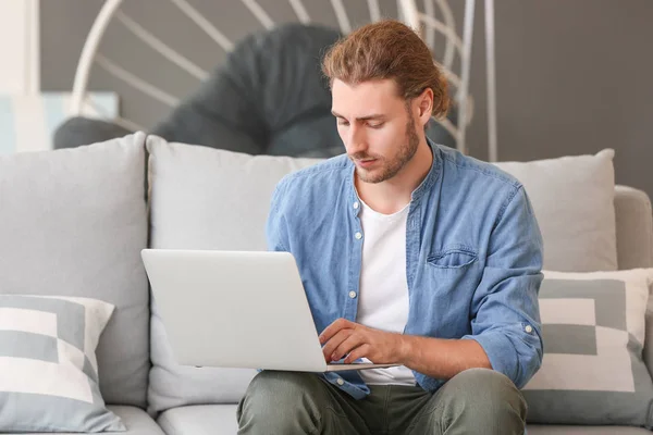 Beau homme avec ordinateur portable sur le canapé à la maison — Photo