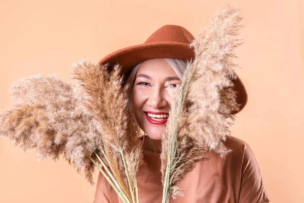 Modieuze rijpe vrouw op kleur achtergrond — Stockfoto