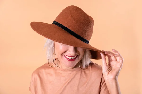 Modieuze rijpe vrouw op kleur achtergrond — Stockfoto