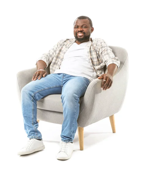 African-American man relaxing in armchair against white background — Stock Photo, Image