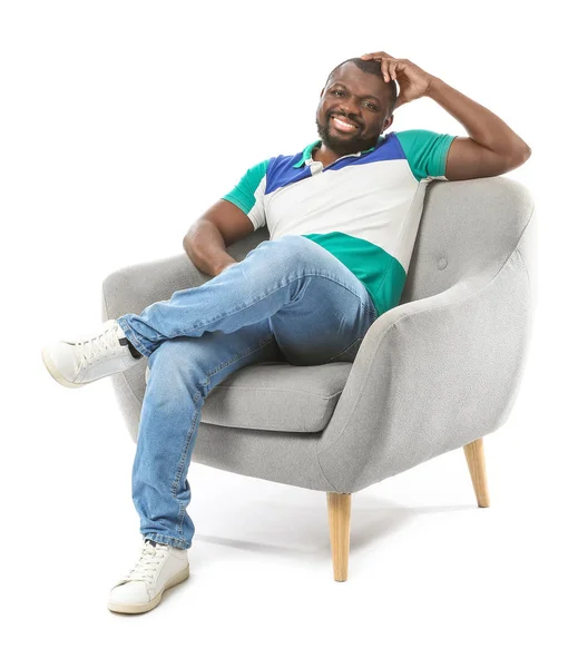 African-American man relaxing in armchair against white background — Stock Photo, Image