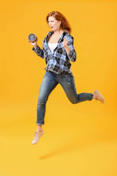 Mujer de salto estresada con reloj despertador sobre fondo de color — Foto de Stock