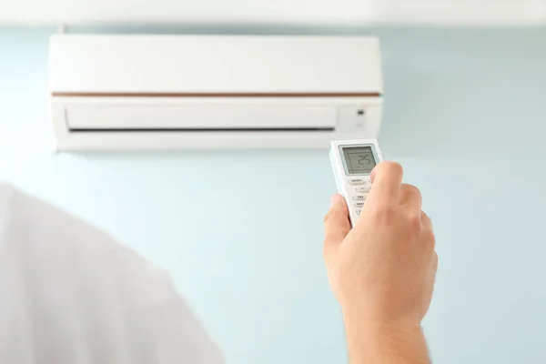 Jovem ligando ar condicionado em casa — Fotografia de Stock