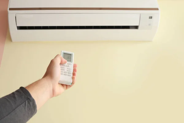 Jovem ligando ar condicionado em casa — Fotografia de Stock