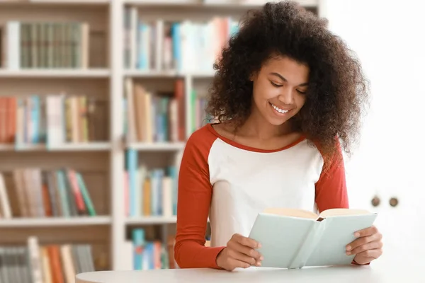 Estudiante afroamericano leyendo libro mientras se prepara para el examen en la biblioteca — Foto de Stock