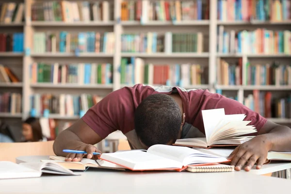 Estudante afro-americano estressado se preparando para exame em biblioteca — Fotografia de Stock