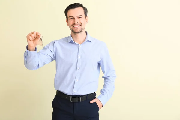 Male real estate agent with key on light background — Stock Photo, Image
