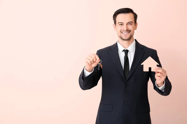 Male real estate agent with key on color background — 스톡 사진
