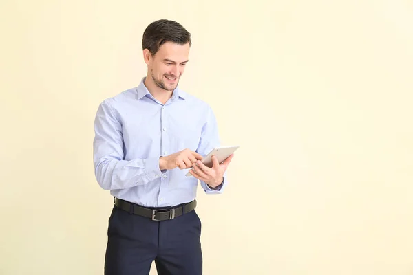 Male real estate agent with tablet computer on light background — Stock Photo, Image