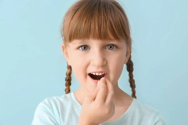 Little girl taking fish oil pill against color background — Stock Photo, Image