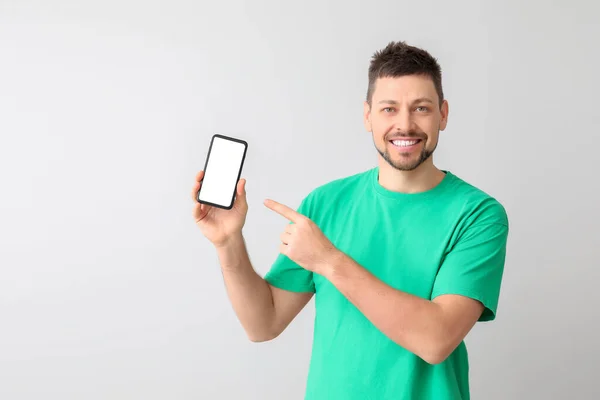 Щасливий чоловік з мобільним телефоном на світлому фоні — стокове фото