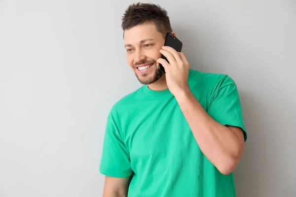 Happy man talking by mobile phone on light background — Stock Photo, Image