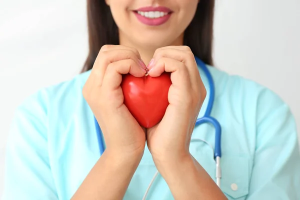 Жіночий кардіолог з червоним серцем на світлому фоні, крупним планом — стокове фото