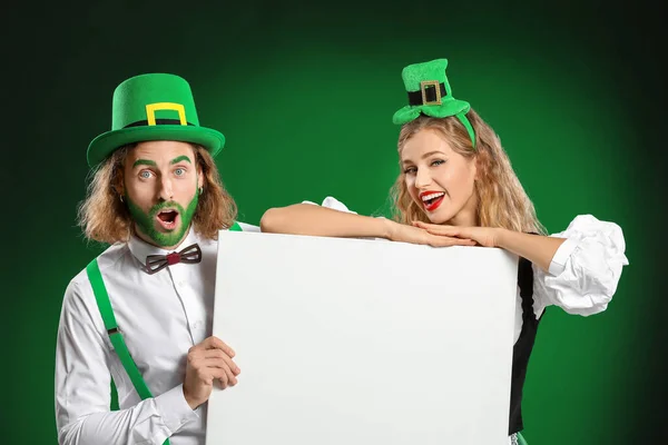 Young couple with blank poster on color background. St. Patrick's Day celebration — Stock Photo, Image