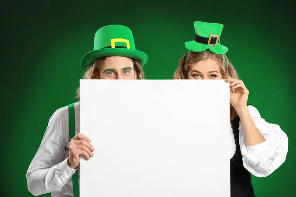 Young couple with blank poster on color background. St. Patrick's Day celebration — 스톡 사진