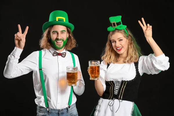 Jong stel met bier op donkere achtergrond. St. Patrick 's Day viering — Stockfoto