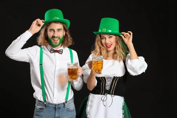 Casal jovem com cerveja no fundo escuro. Celebração do Dia de São Patrício — Fotografia de Stock