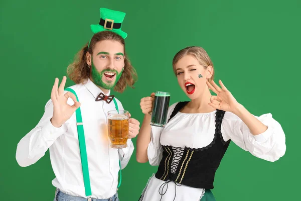 Jong stel met bier te zien Ok op kleur achtergrond. St. Patrick 's Day viering — Stockfoto