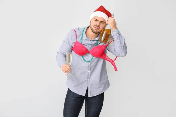 Drunk man with Santa Claus hat and champagne on light background — Stock Photo, Image