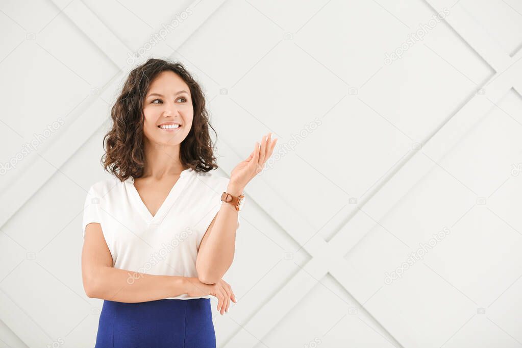 Portrait of beautiful businesswoman showing something on grey background