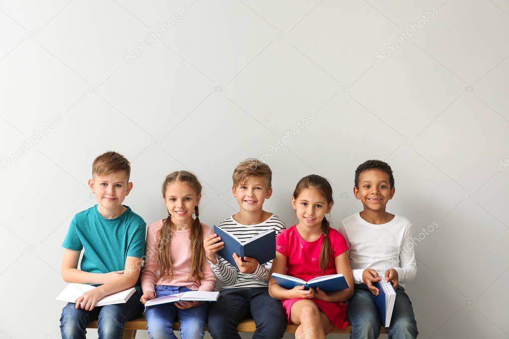 Cute little children reading books on grey background