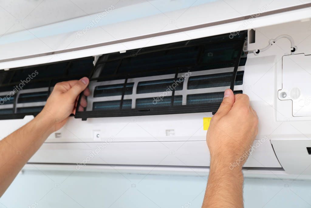 Male technician repairing air conditioner indoors, closeup