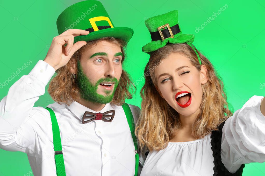 Young couple taking selfie on color background. St. Patrick's Day celebration