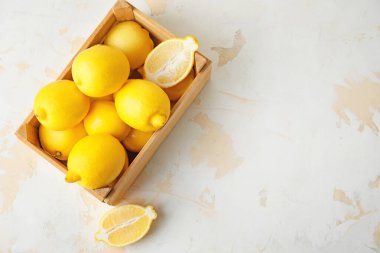 Masada taze olgun limonlarla dolu bir kutu.