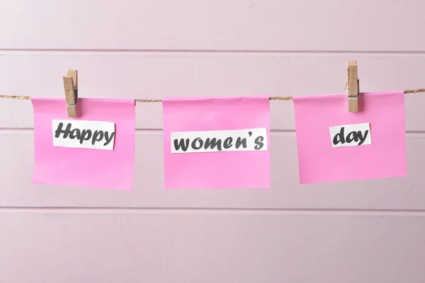 Ευχετήριες κάρτες για την Παγκόσμια Ημέρα της Γυναίκας κρεμασμένες σε σχοινί σε λευκό ξύλινο φόντο — Φωτογραφία Αρχείου