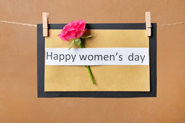 Uluslararası Kadınlar Günü için tebrik kartı renk arkaplanına karşı ipte asılı — Stok fotoğraf