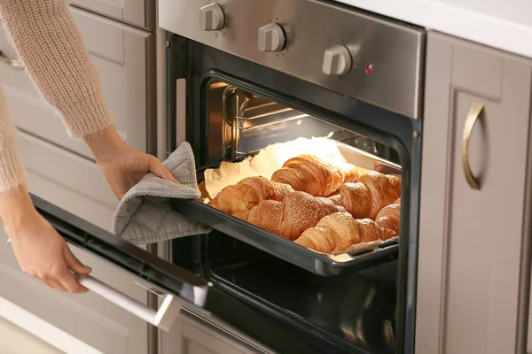 Mulher tomando bandeja de cozimento com croissants frescos fora do forno — Fotografia de Stock