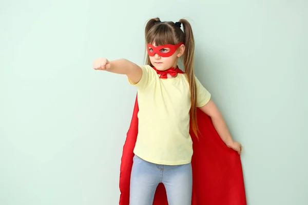 Little girl in superhero costume on color background. Concept of feminism — Stock Photo, Image