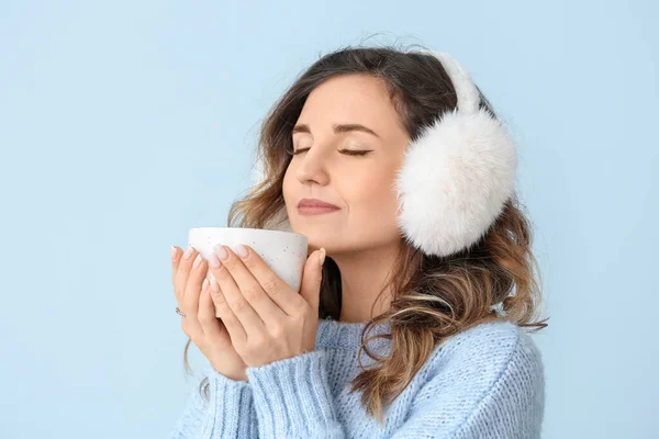 Hermosa mujer joven en suéter cálido y con té caliente sobre fondo de color — Foto de Stock