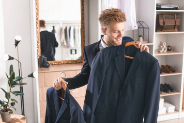 Soyunma odasında kıyafet seçen yakışıklı bir adam.