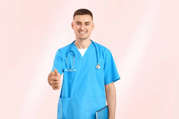 Male medical student showing thumb-up gesture on color background — Stock Photo, Image