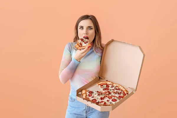 Portrait of beautiful young woman eating pizza on color background — Stock Photo, Image