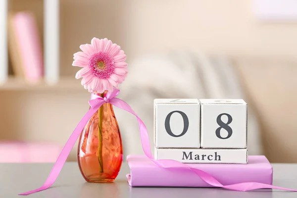 Calendario con la fecha del Día Internacional de la Mujer, flor y libro en la mesa en la habitación — Foto de Stock