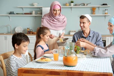 Müslüman bir aile evde yemek yiyor.