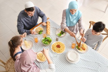 Müslüman bir aile evde yemek yiyor.