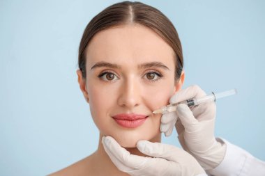 Genç kadın renk arkaplanına karşı doldurucu enjeksiyon alıyor